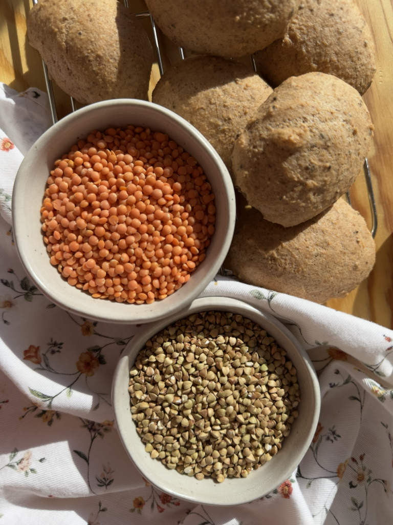 Lentejas rojas y granos de trigo sarraceno en bowls junto a panecillos sin gluten recién horneados