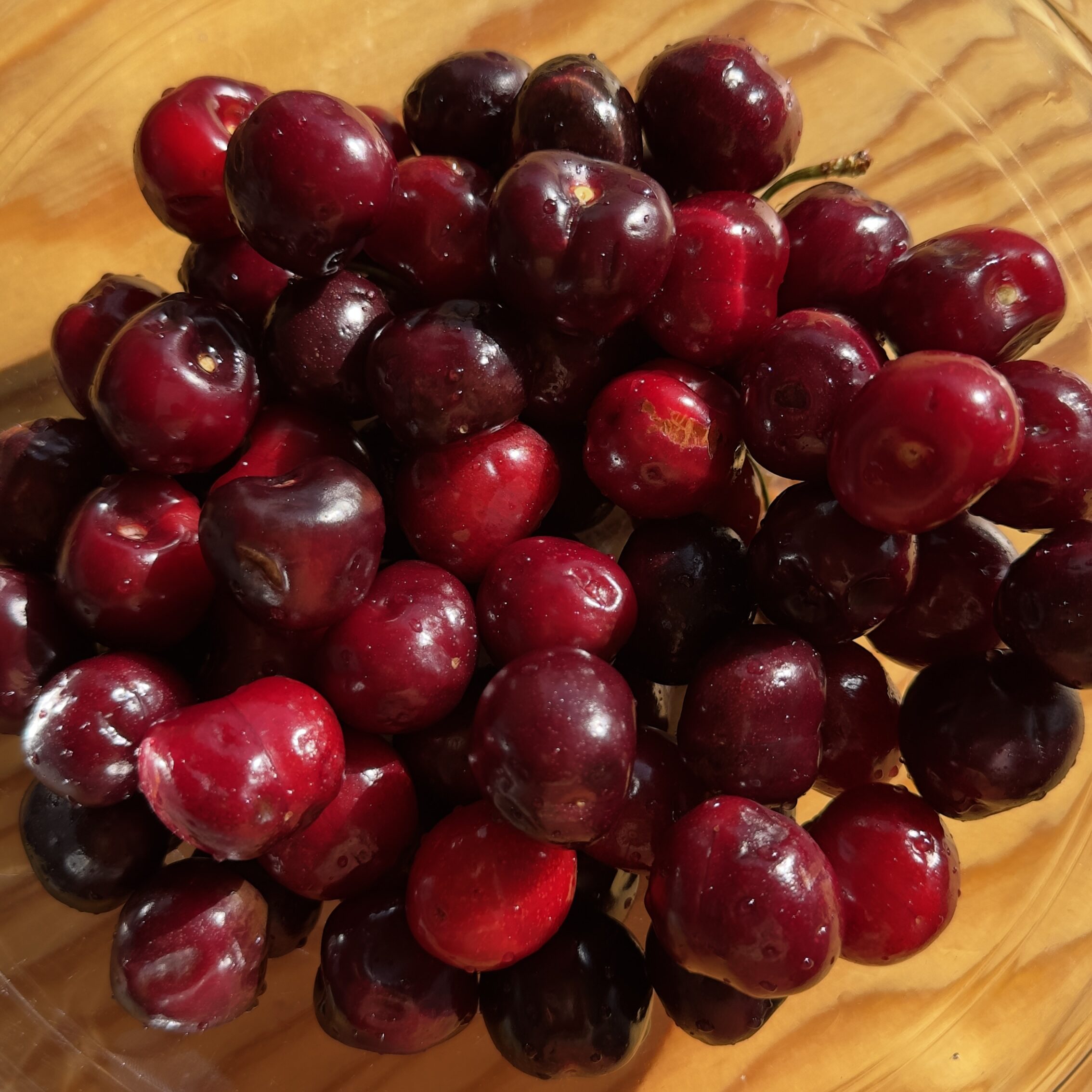 Cerezas frescas de temporada en bol de cristal sobre mesa de madera