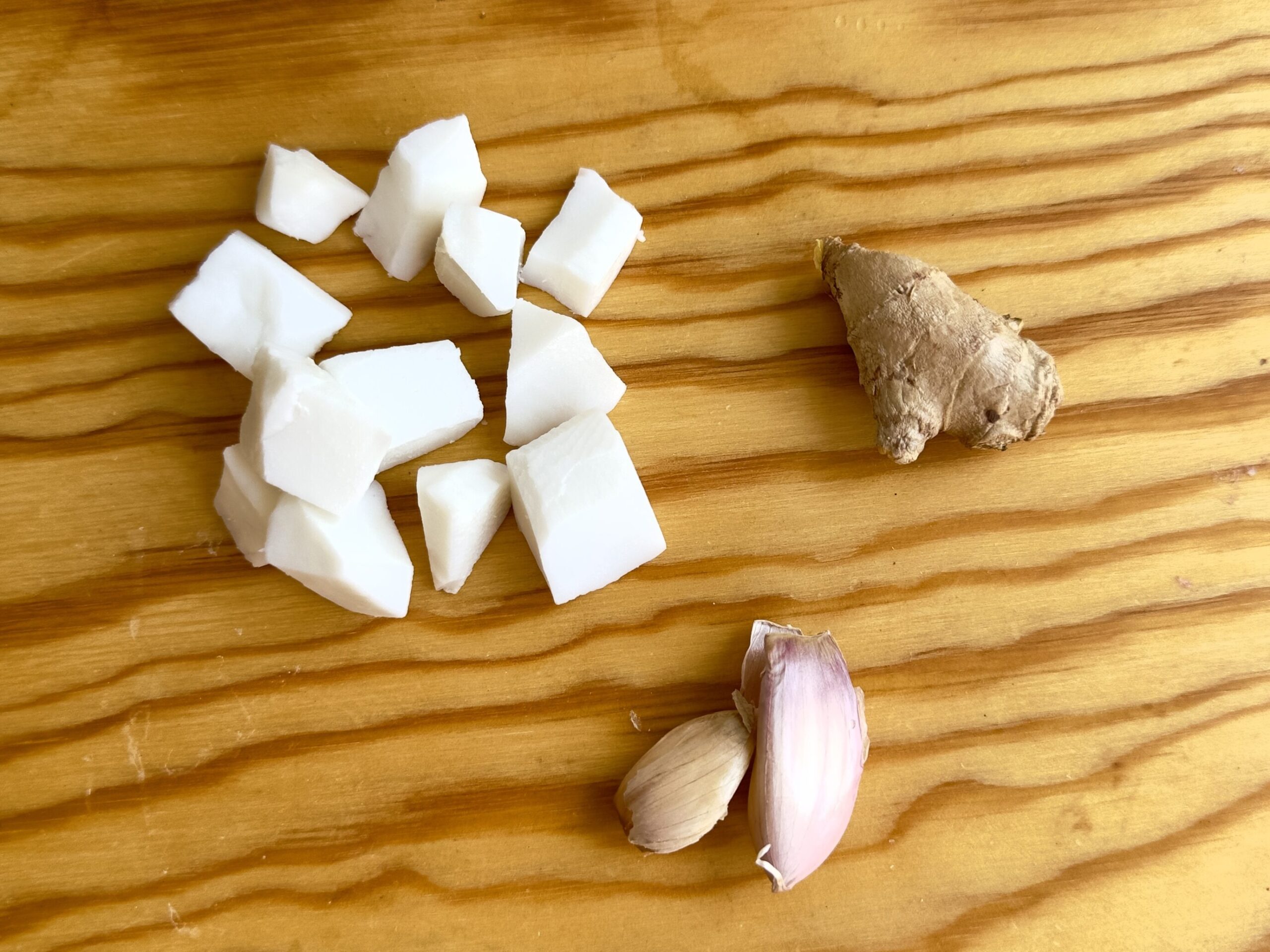 Trozos de pulpa de coco fresca junto a un trozo de jengibre y dos dientes de ajo